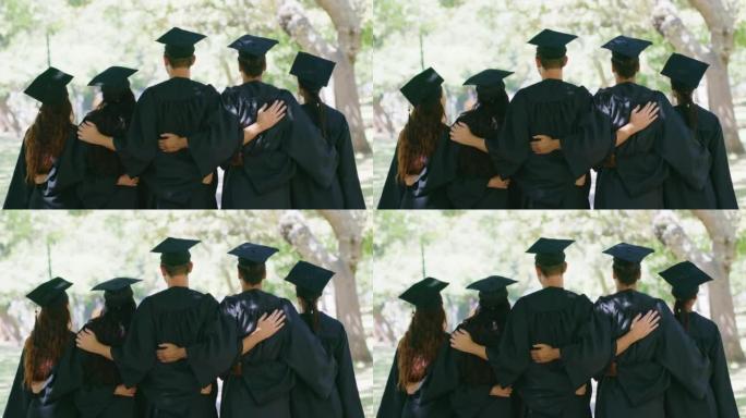 毕业时站在一起的学生后方。一群成功的毕业生与帽子和长袍团结一致，并在大学获得文凭证书后感到很成功