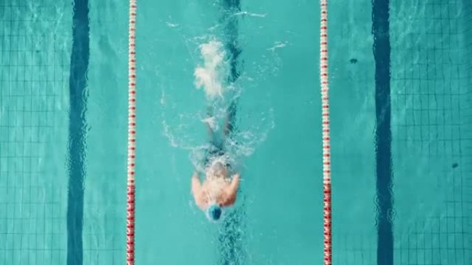 空中俯视图男游泳者在游泳池中，以创纪录的速度跑圈。专业运动员训练比赛，赢得世界冠军蝶泳风格。电影宽固