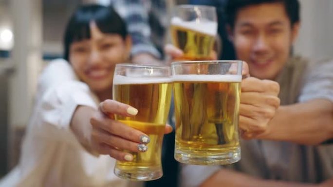 一群亚洲年轻人使用手机在远程视频通话中问候朋友，喝酒精啤酒并在夜间咖啡馆举行聚会。