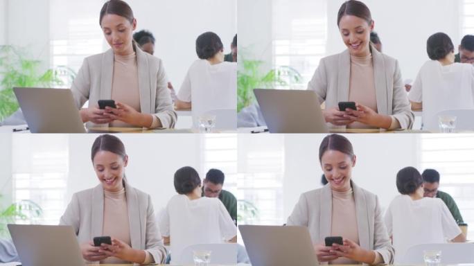 快乐的年轻女商人坐在笔记本电脑旁，用电话浏览互联网。在现代繁忙的办公室中的一家初创公司检查社交媒体的