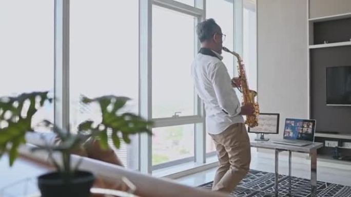 lifehack亚洲活跃的高级艺术家演奏萨克斯管，并在客厅使用笔记本电脑向学生展示