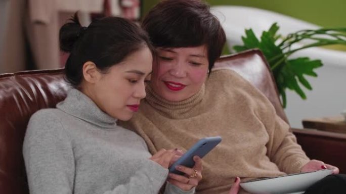漂亮的亚洲女人和中年妈妈玩手机
