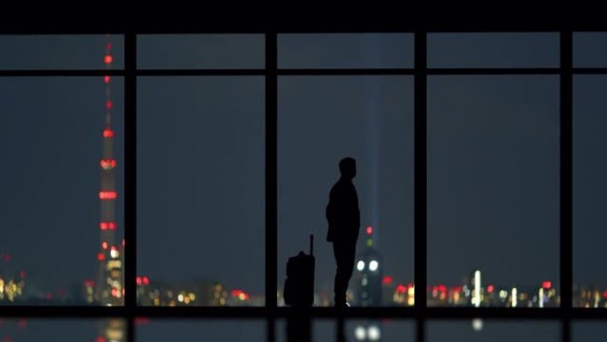 那个带手提箱的男人站在室内夜景背景下。时间流逝