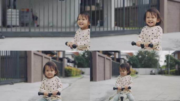 快乐的亚洲小女孩骑着蹒跚学步的踏板车。