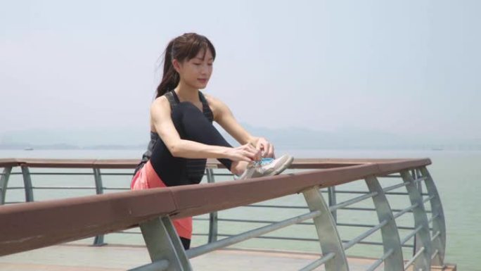 年轻的亚洲女运动员系鞋带准备锻炼