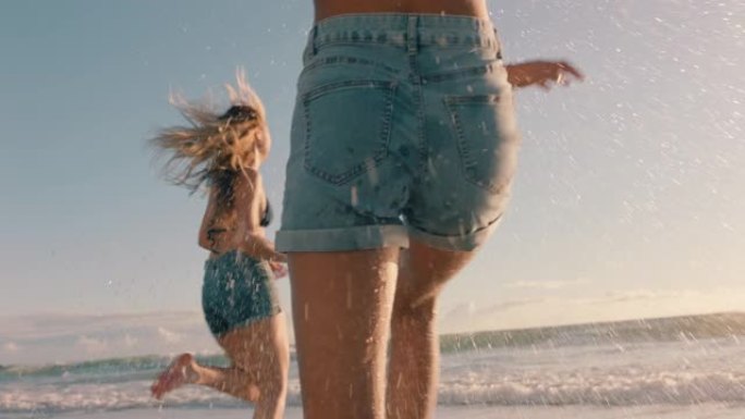 两个女人在海滩上互相泼溅海水，在温暖的夏日里，十几岁的女孩在海边玩游戏，享受夏日假期