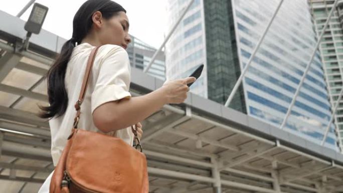 亚洲妇女在城市的街道上使用手机