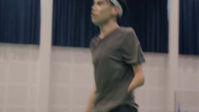一名残疾运动员采取姿势打羽毛球。