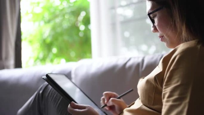 女人在家里沙发上休息时使用数字平板电脑