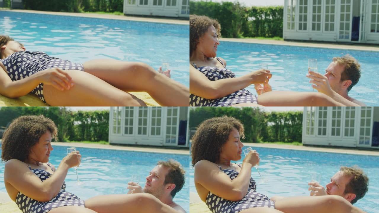 暑假里成熟的女人在室外游泳池边缘晒日光浴，男人带来了一杯香槟来庆祝 -- 慢动作拍摄