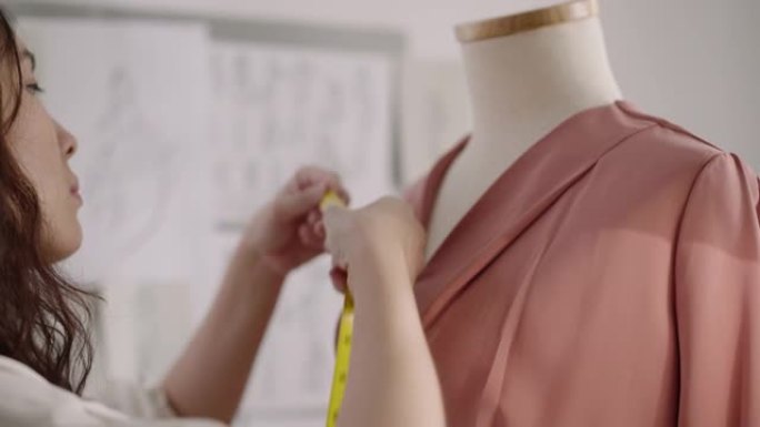 女性设计师在时装设计工作室测量她的设计服装