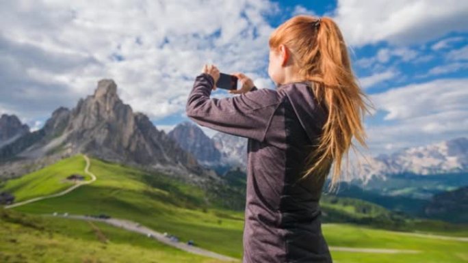 女游客在晴天用智能手机拍摄山景全景