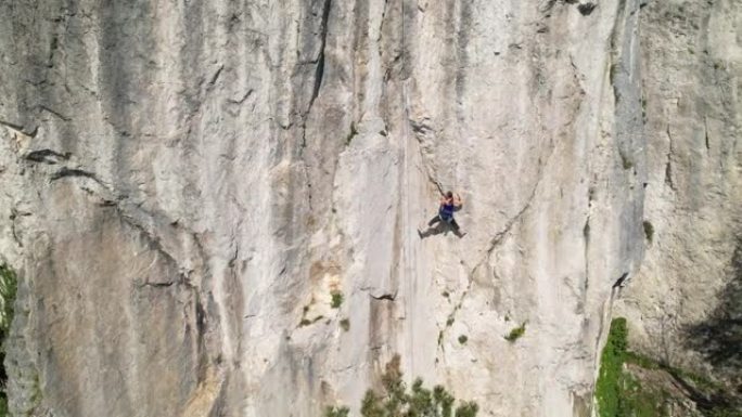 无人机: 女性登山者学习绳索在自然墙中寻找。