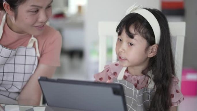 母亲教女儿使用数字平板电脑进行在线学习
