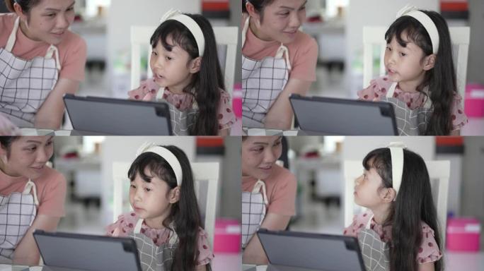 母亲教女儿使用数字平板电脑进行在线学习