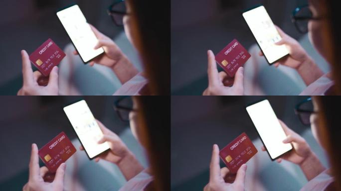 亚洲女性使用智能手机在客厅沙发上订购带信用卡的网上购物产品