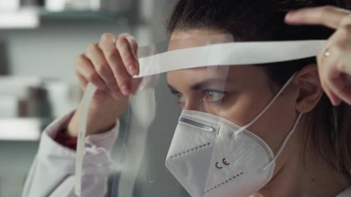 女药剂师顾问在药房戴上N95防护口罩和遮阳板的电影宏观镜头。概念: 新型冠状病毒肺炎、保护、冠状病毒