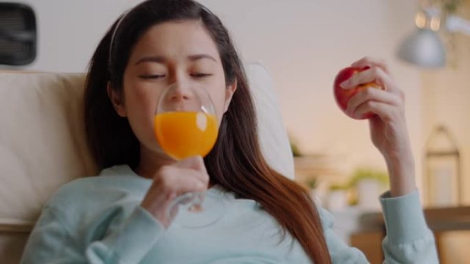 快乐孕妇在家吃一个新鲜的红苹果，喝橙汁。