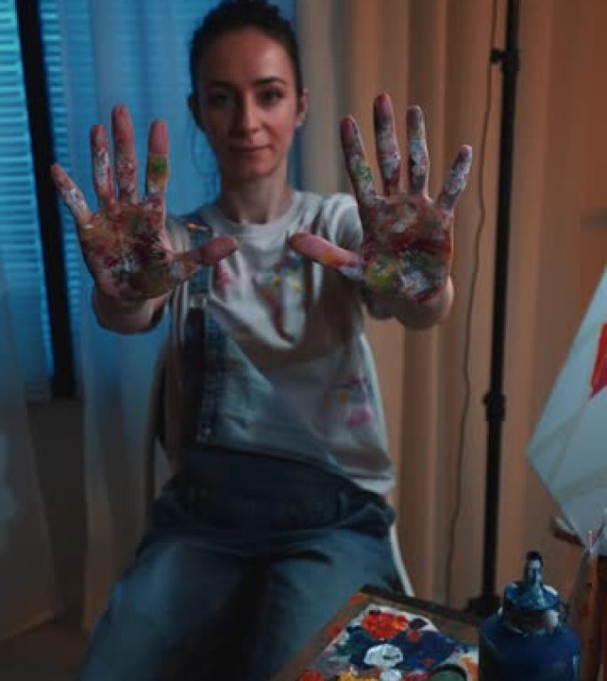 一位展示多色脏手的女艺术家肖像。