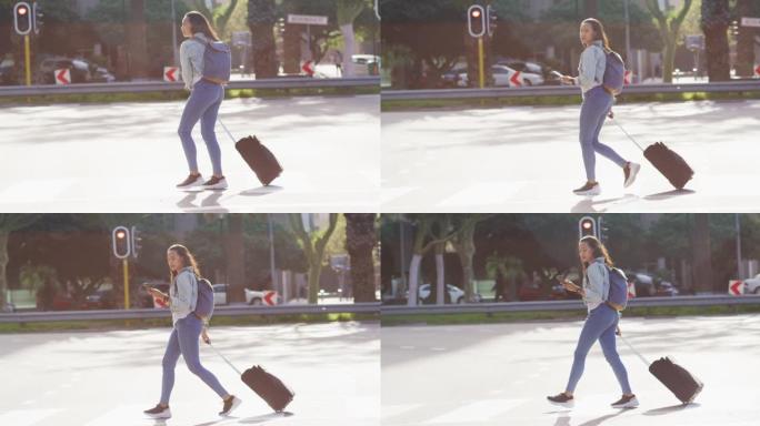 亚洲妇女使用智能手机行走并拖着手提箱