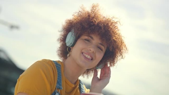 放松，城市和屋顶上有手机音乐的女人享受自由、无忧无虑的生活方式和健康。戴着耳机、智能手机和流媒体歌曲