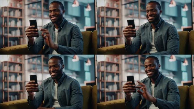 兴奋的黑人非洲裔美国人在客厅的沙发上休息时使用智能手机。快乐的男人在家里微笑，通过互联网与同事和客户