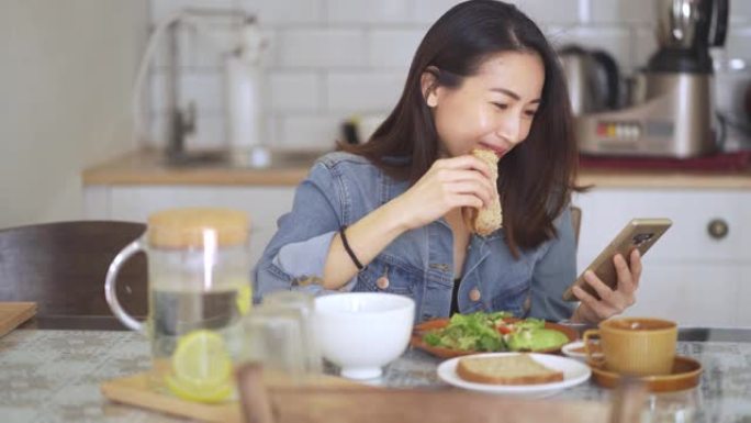 亚洲中国美女在家享用早餐，吃面包花生酱和咖啡