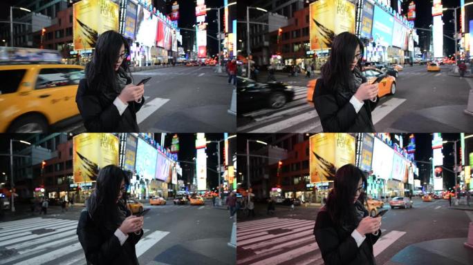 亚洲女子夜间在时代广场使用智能手机