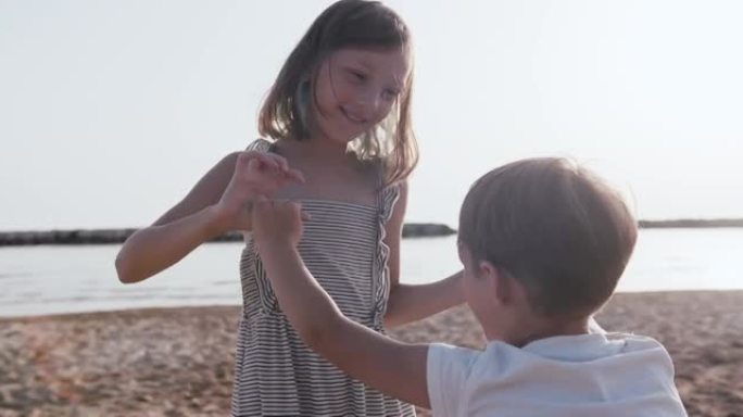 特写两个快乐的孩子在日出海滩玩得开心，和年轻的母亲和朋友一起慢动作。