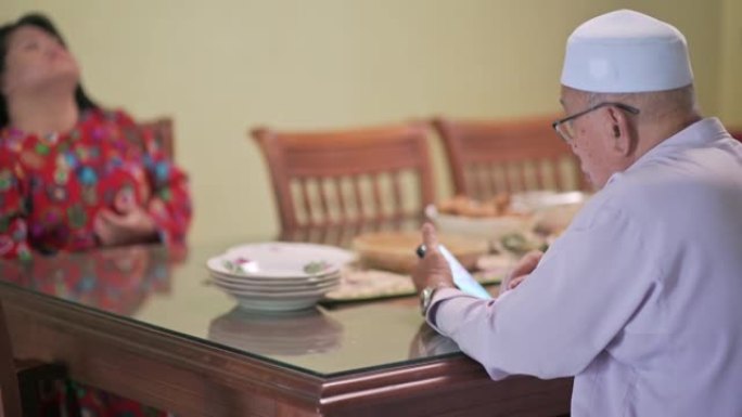 马来西亚马来曾祖父坐在餐厅看着他的智能手机检查电话信息