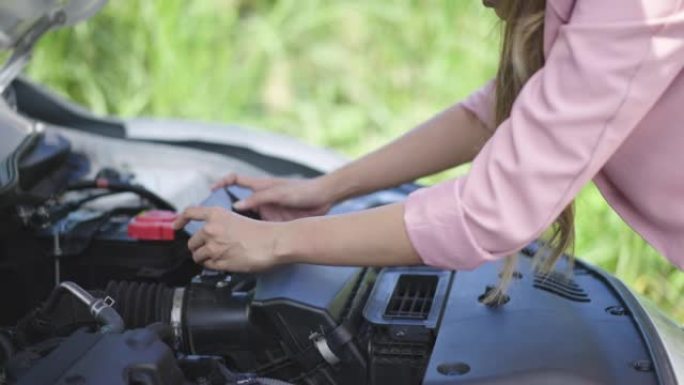 年轻女子对汽车故障有问题，并拍照到汽车机器上，以发送给机械师检查