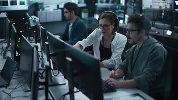 年轻的专家团队在台式计算机上工作，并在工作场所进行对话。男女软件开发人员讨论其人工智能项目的解决方案