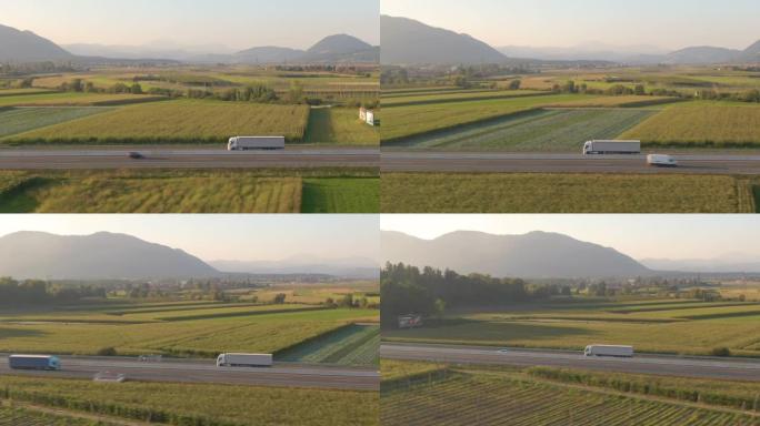 空中: 沿着一辆白色半卡车飞行，沿着风景秀丽的高速公路拖运货物。