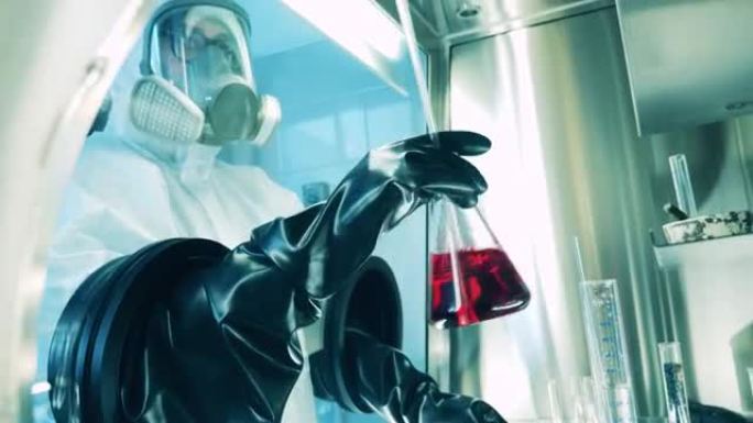 专家正在真空柜中使用一个锥形烧瓶。Covid-19、冠状病毒实验室、病毒、大流行概念。