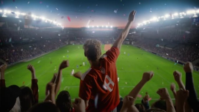 在足球锦标赛期间，在体育场上建立球迷为球队欢呼的镜头。球队进球，一群球迷尖叫，用五彩纸屑庆祝胜利。足