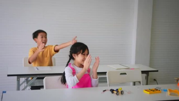 在教室里展示机器人编码项目后，一群小学生向他们的朋友鼓掌。初等教育、技术