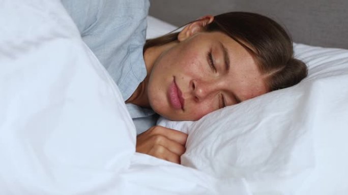 熟睡的年轻女士躺在舒适的床上，抱着柔软的枕头