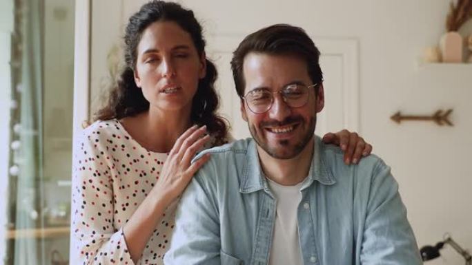 微笑的年轻欧洲家庭夫妇举行视频通话对话。