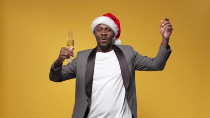 皮肤黝黑的微笑男子在圣诞晚会上，旋转一杯香槟，随着轻音乐跳舞