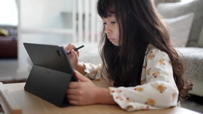 小女孩在家在数字平板电脑上画画