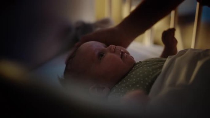 一位母亲在婴儿床中抚慰和拥抱一个新生男婴的真实特写镜头。白人新生儿蹒跚学步的孩子在孩子们的卧室里。童