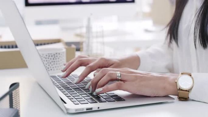 在现代办公室中使用笔记本电脑的无法识别的女商人的4k视频片段