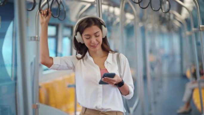 女人在地铁通勤时拿着扶手听音乐