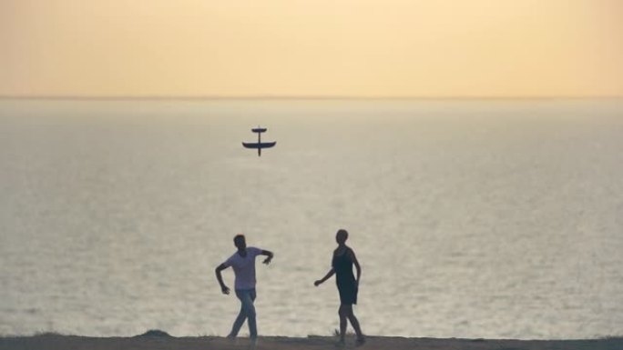 男人和女人在海滩上扔玩具飞机。慢动作
