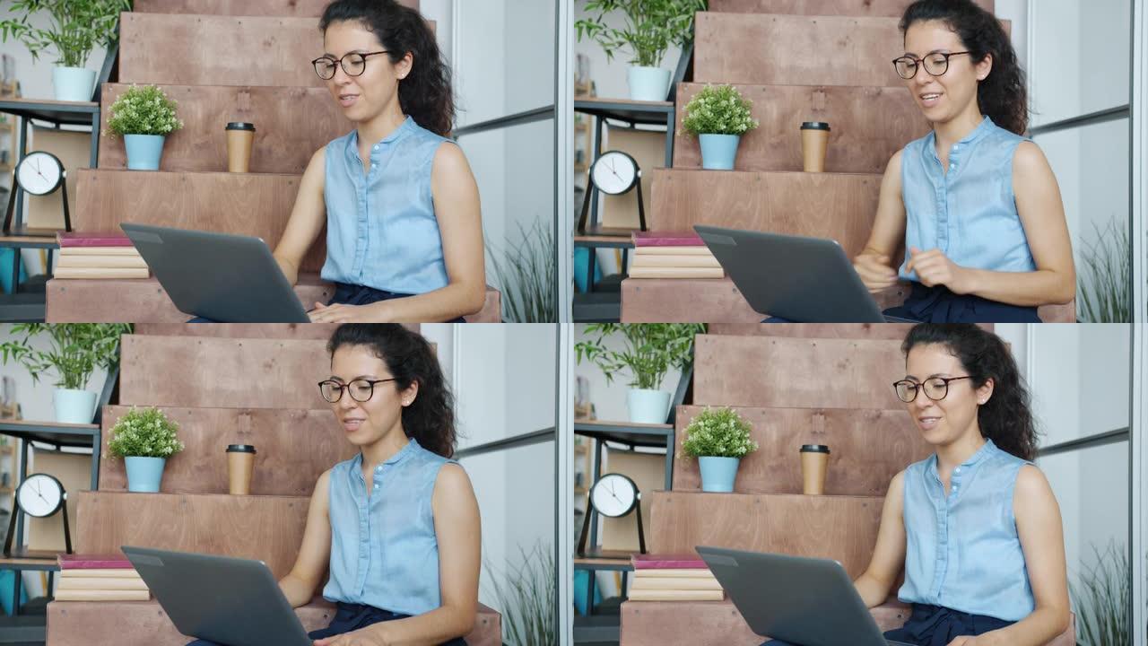 美丽的混血女人在办公室使用笔记本电脑进行在线视频通话