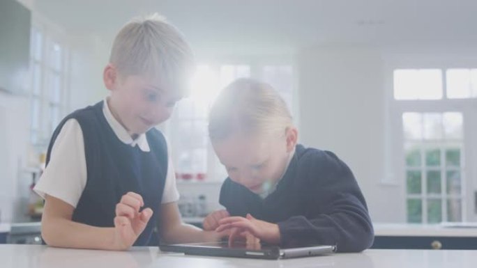两个穿着校服的孩子在厨房里玩柜台上的数字平板电脑