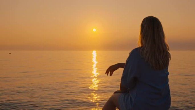 日落时在海滩上放松的女人的SLO MO剪影