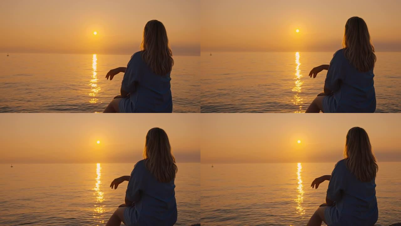 日落时在海滩上放松的女人的SLO MO剪影
