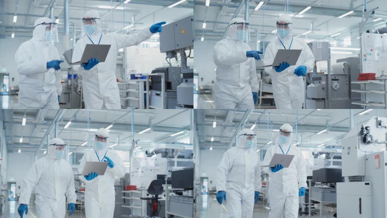 两名科学家穿着无菌工作服和口罩，在一家重工业工厂里行走，使用笔记本电脑。检查工业机器设置并配置生产功