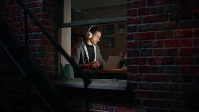 软件开发人员深夜在笔记本电脑上编程。男性专家浏览互联网，听播客，做创意营销。远程在家工作的概念。从户